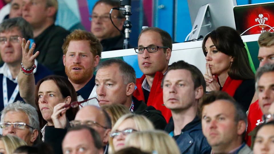 Prinz Harry, Prinz William und Herzogin Kate schauen sich ein Rugby-Spiel an.