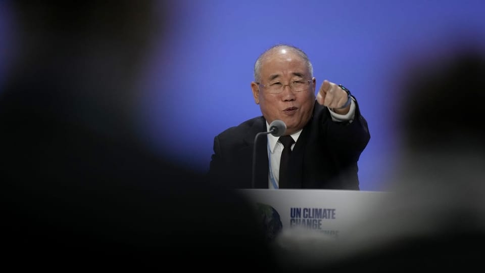 Zhenhua zeigt an der Pressekonferenz auf eine Journalistin und wirkt erheitert.