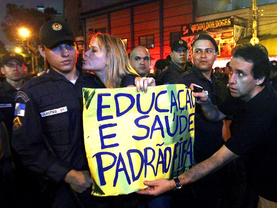 Brasilianische Demonstranten halten ein Transparent hoch, auf dem sie mehr Schulen und bessere Erziehung fordern.