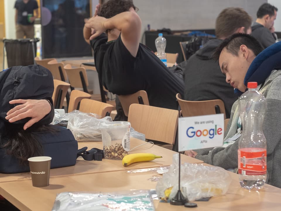 Zwei schlafende Hacker an einem Tisch.