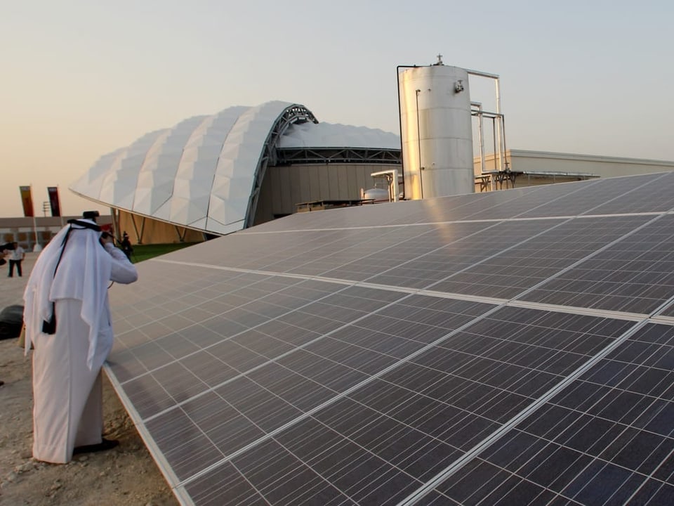 Ein Mann steht neben einem grossen Solarpanel.