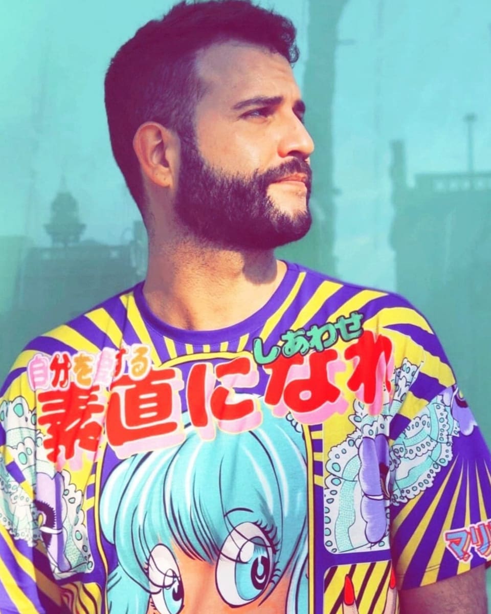 Ein junger Mann in einem bunten Shirt mit Manga-Motiv posiert für die Kamera