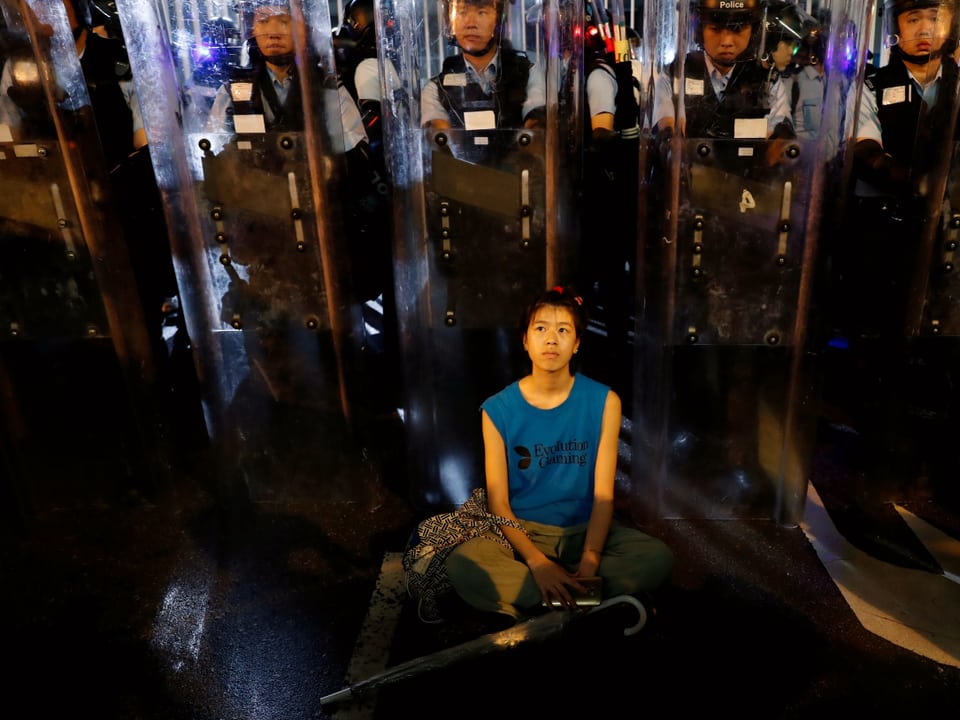 Frau demonstriert sitzend vor Polizisten
