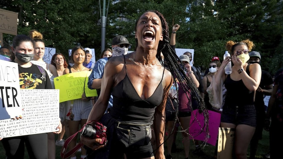 eine schwarze Frau schreit in eine Menschengruppe