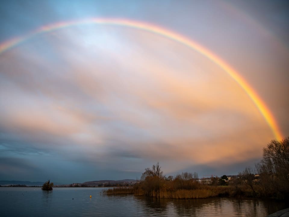Vollständiger Regenbogen über einem See.