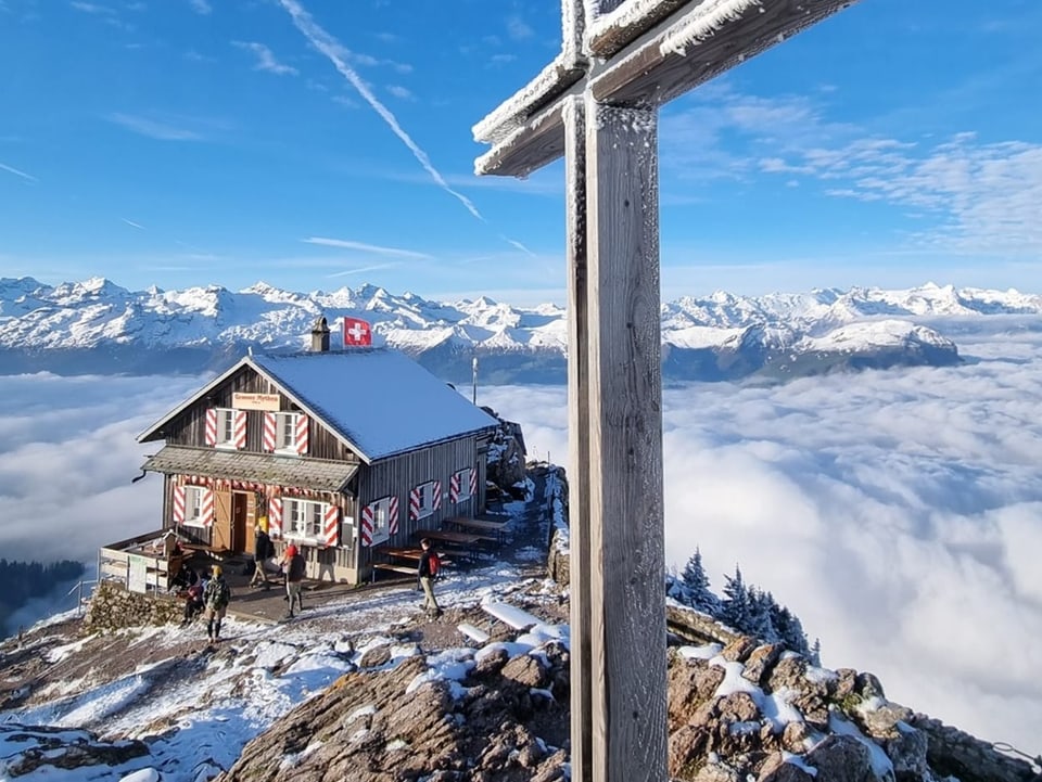 Gipfel mit Kreuz und Hütte, dahinter Nebelmeer im Tal