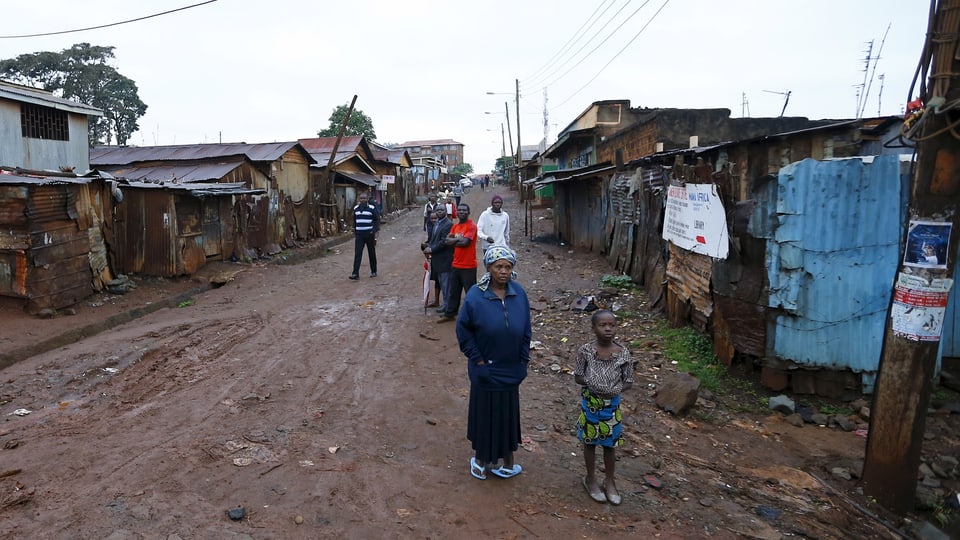 Menschen stehen auf der Strasse eines Slums in Nairobi.