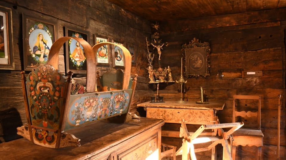 Ein altes Wohnzimmer, alles aus Holz, christliche Gemälde an der Wand.
