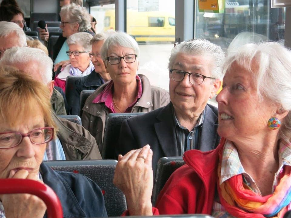 Mehrere Menschen sitzen gespannt in einem Bus.
