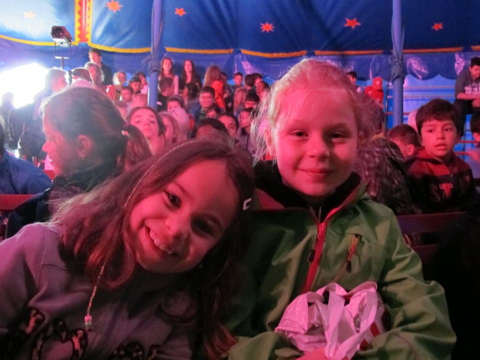 Fröhliche Kinder im Publikum im Zirkuszelt.