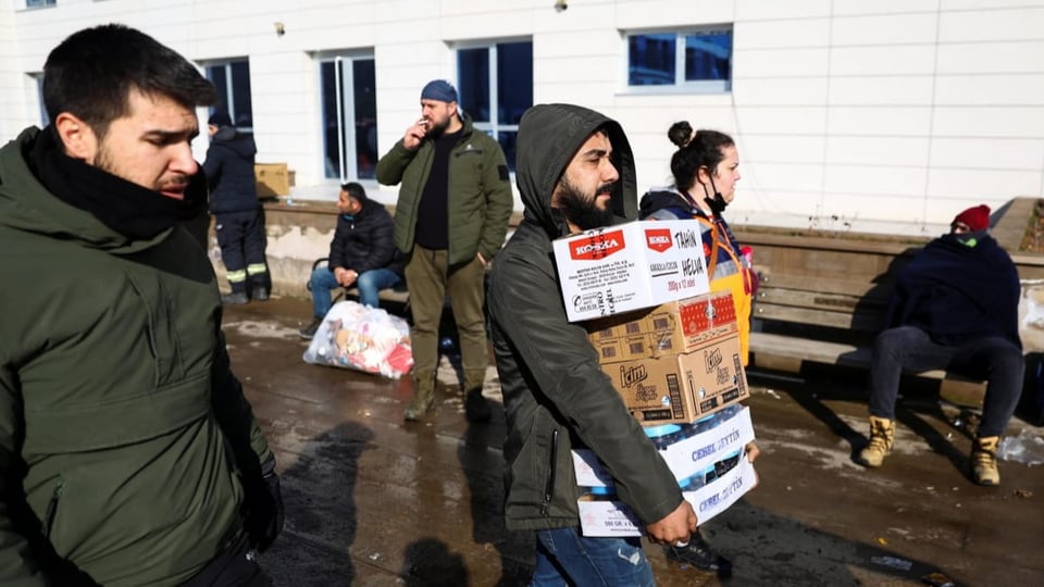 Helfer tragen Kartonkisten mit Essen für vom Erdbeben betroffene Menschen.