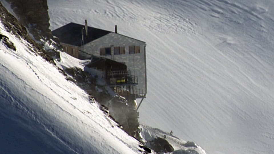 Eine SAC-Hütte oberhalb eines Schneefeldes.