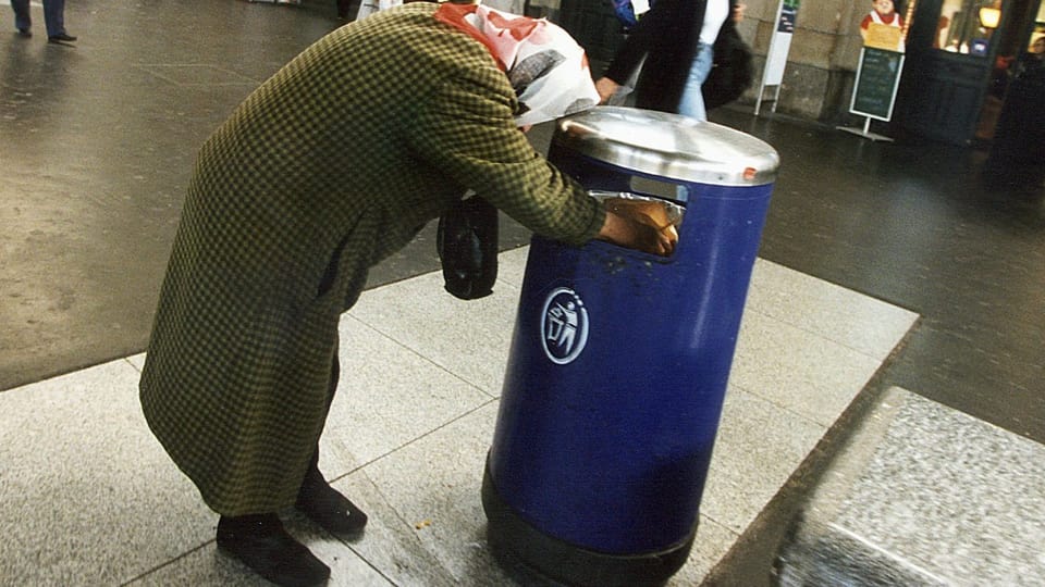Eine Frau durchsucht einen Abfalleimer im Bahnhof Zürich.