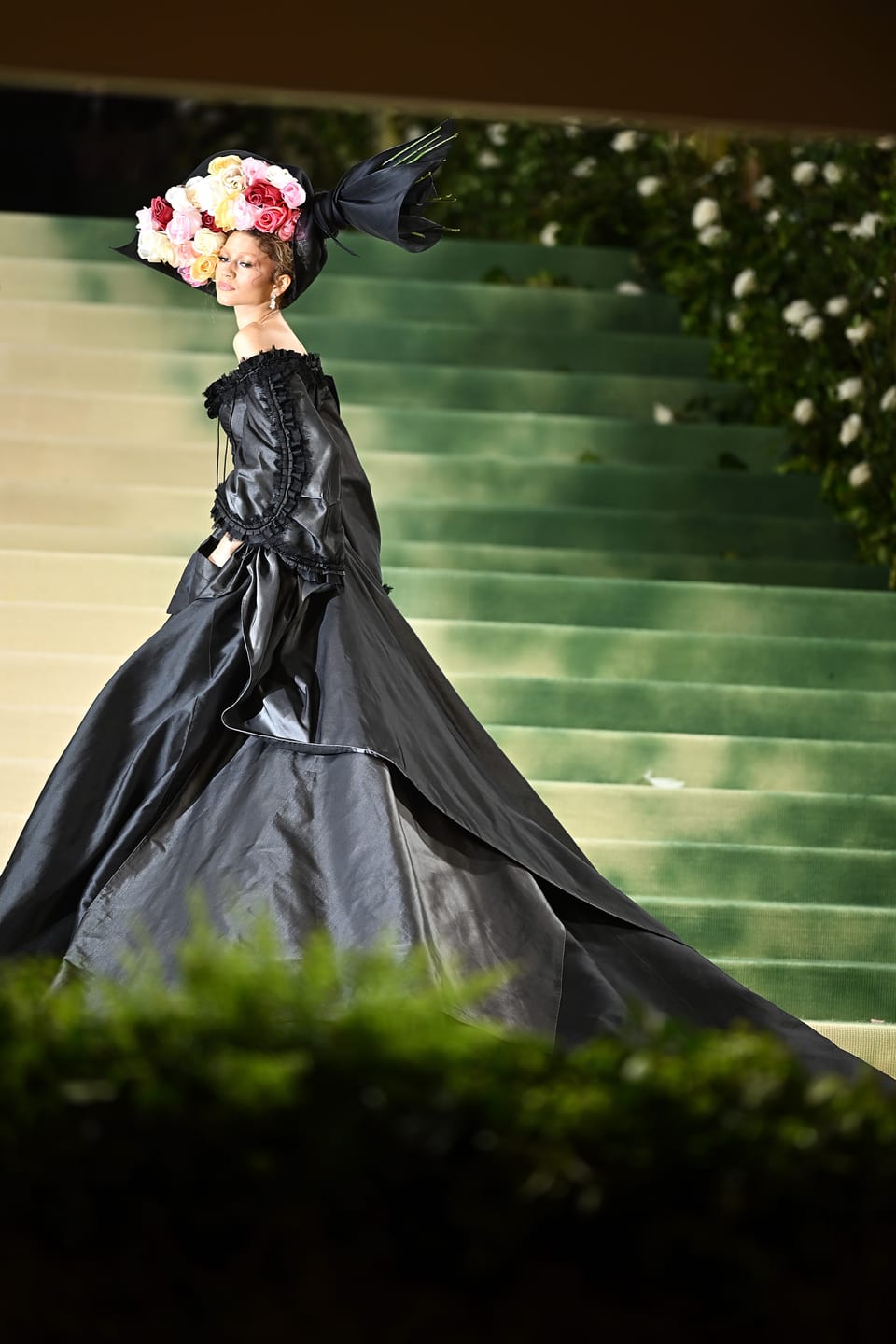 Frau in schwarzer Robe mit Blumenschmuck auf dem Kopf
