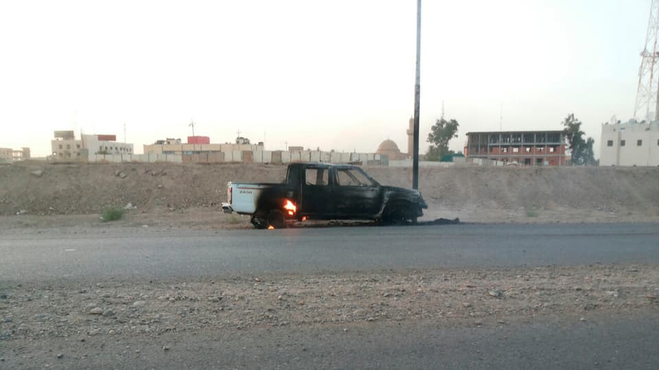 Auf einer Strasse in Tikrit steht ein ausgebranntes Auto