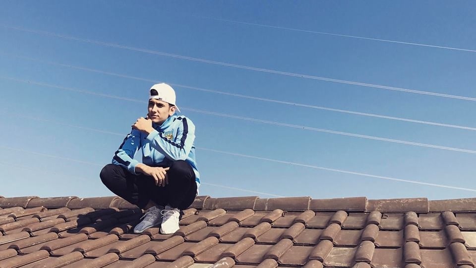 junger Rapper sitzt auf einem Dach