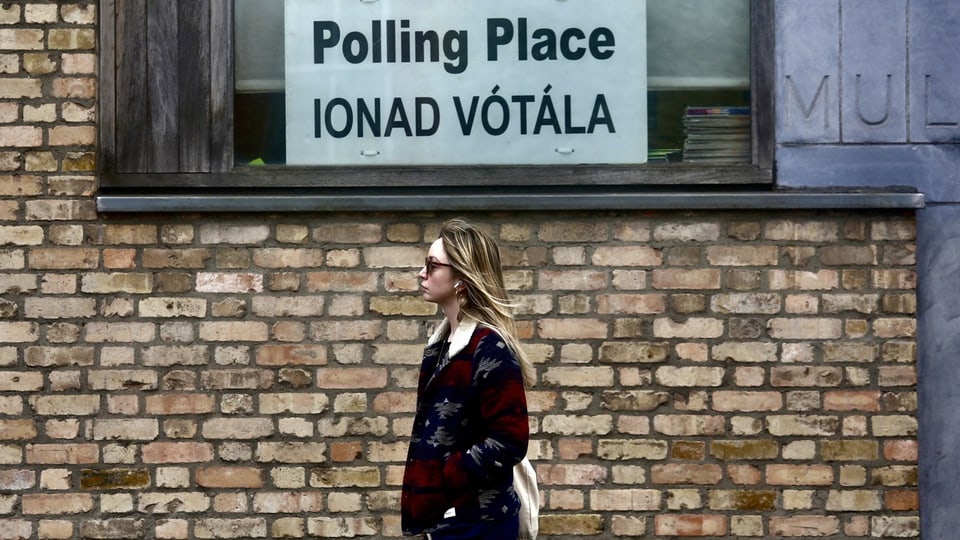 Frau geht vor Schild mit Aufschrift «Polling Place» vorbei