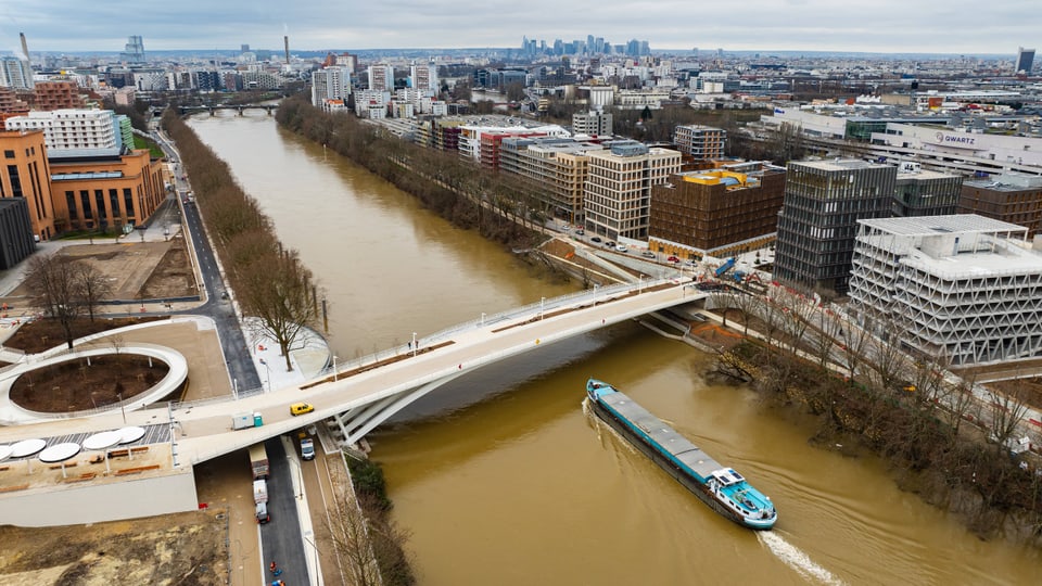 Luftbild einer Stadt mit Fluss, Brücke und Schiff.