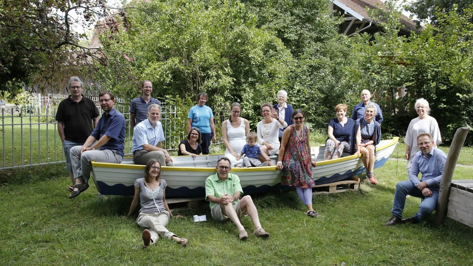 eine Gruppe von Menschen sitzt im Garten in einem Ruderboot