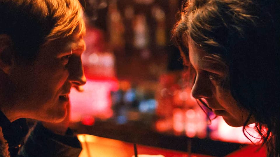 Georg (Georg Freidrich) und Marija (Margarita Breitkreiz) sitzen sich in einer Bar nahe gegenüber.