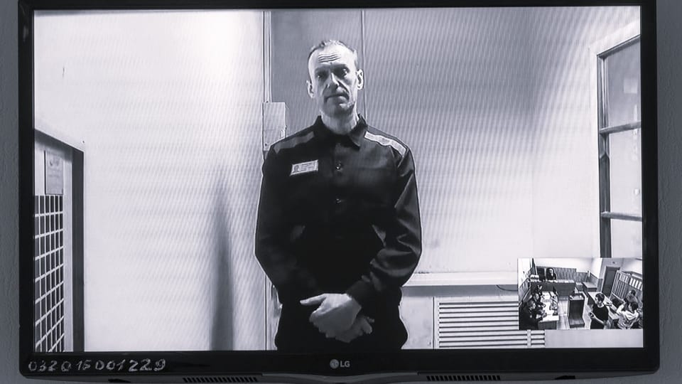schwarzweiss-Foto Nawalny in Haftkleidung vor einem Bildschirm, schaut einem an