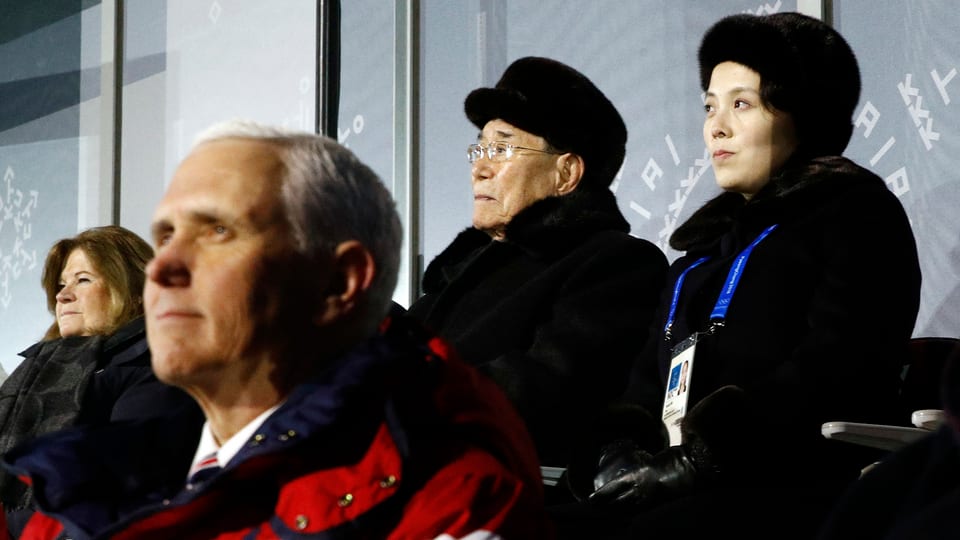Pence und die Schwester sitzen hintereinander in zwei Reihen bei der Eröffnungsfeier der Olympischen Spiele.