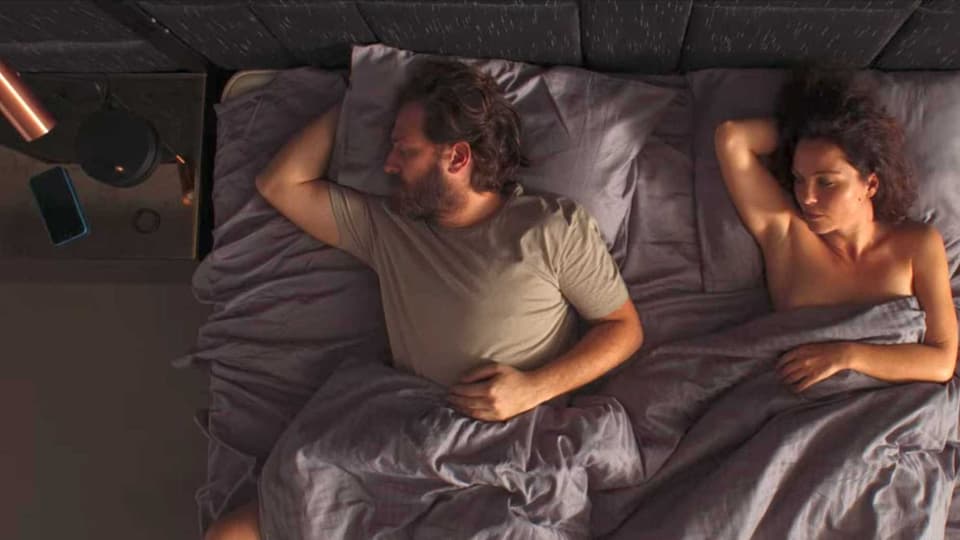 Ein Mann und eine Frau liegen nebeneinander im Bett