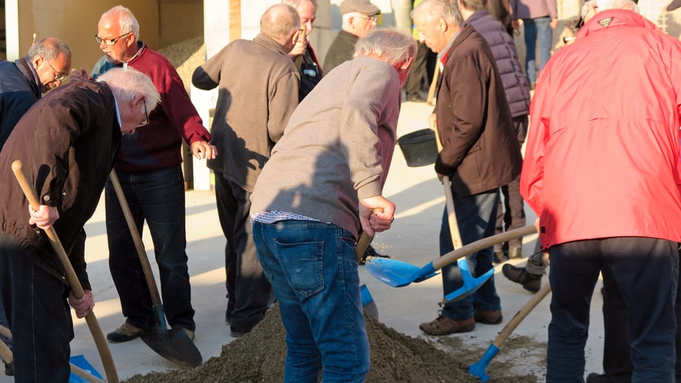 Sänger schaufeln Sand von einem Haufen.