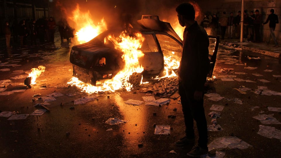 Protestierender vor einem brennenden Auto.
