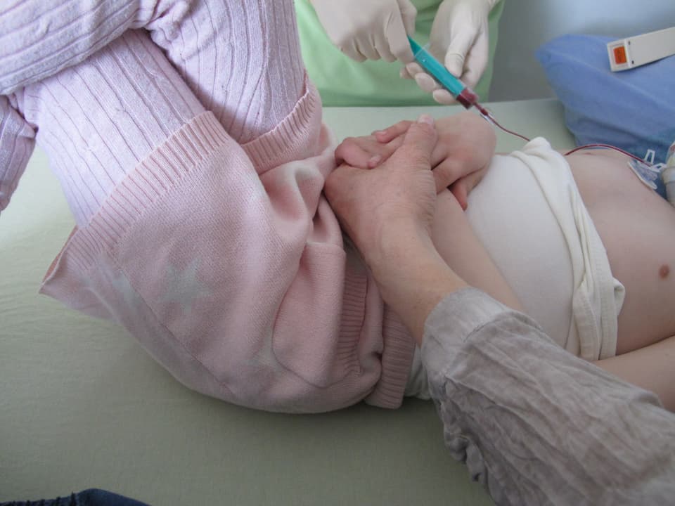 Eine Erwachsenenhand hält eine Kinderhand.