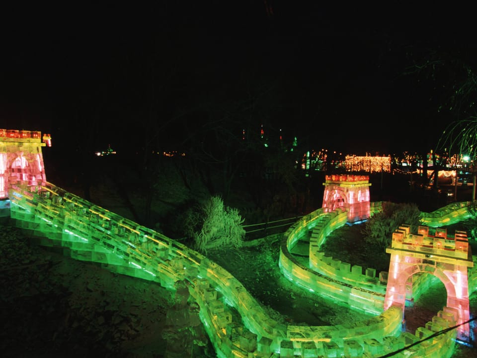 Ein Nachbau der Chinesischen Mauer aus Eis, der rot und grün beleuchtet ist.