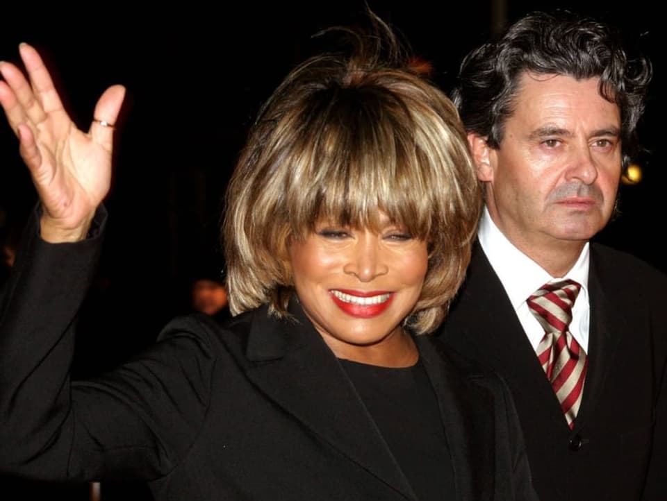 Tina Turner winkt in die Kamera, neben ihr ist ihr Partner Erwin Bach