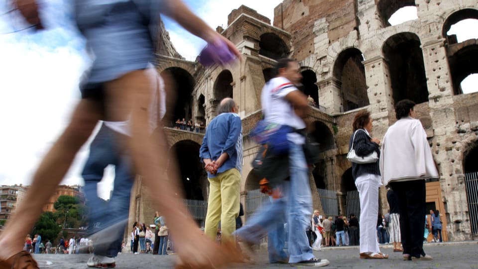 Touristen laufen am Kolosseum vorbei.