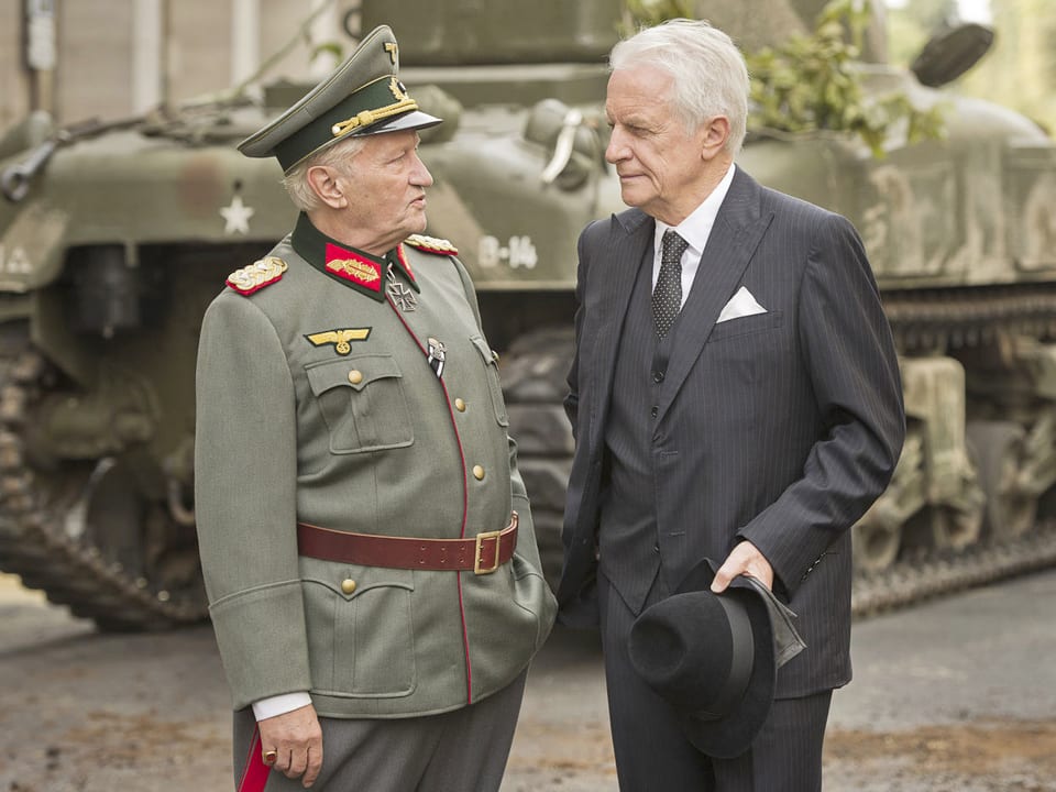 Ein General und ein Diplomat vor einem Schützenpanzer.