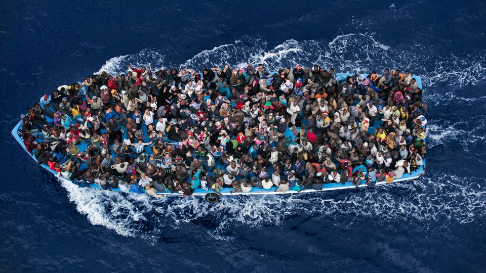 Flüchtlingsboot aus der Vogelperspektive. Boot ist völlig überfüllt.