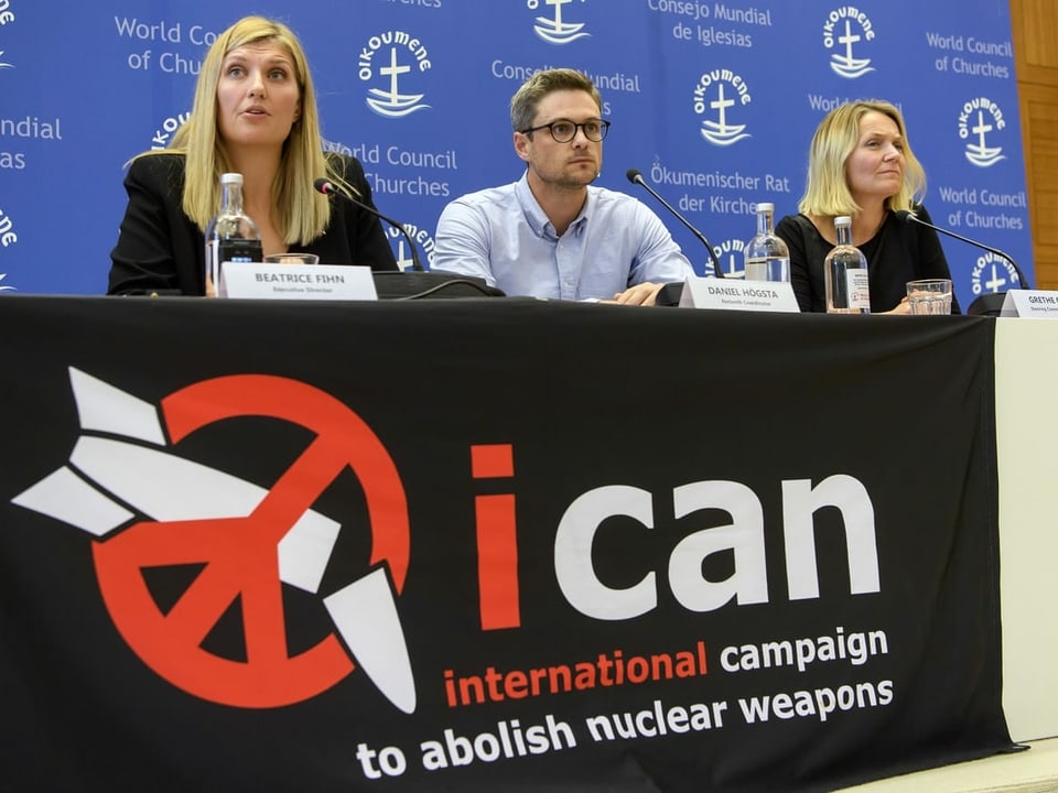 Ican-Vertreter vor einem Banner mit dem Logo der Organisation.