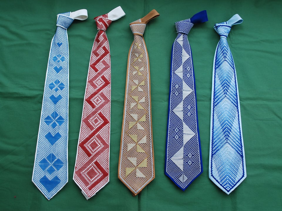 Fünf farbige Krawatten vor grünem Hintergrund.