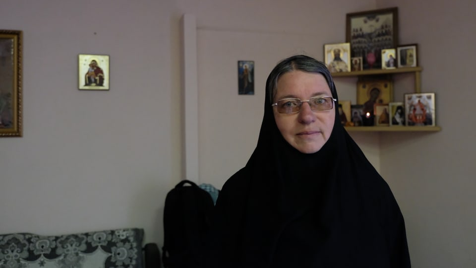 Schwester Nikona in einer schwarzen Robe mit Brille. 
