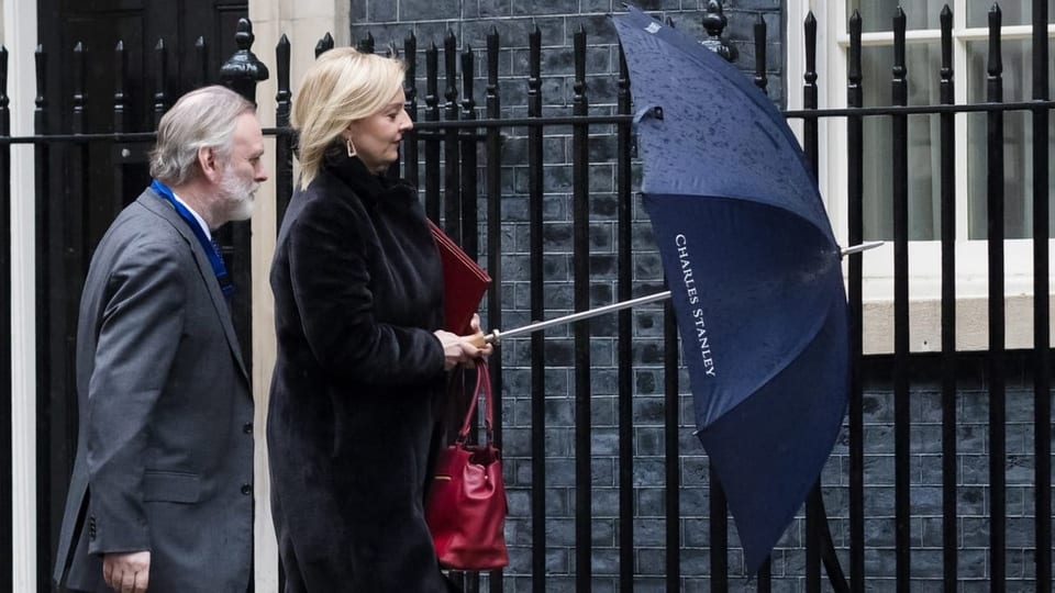 Liz Truss mit einem Begleiter vor der Downing Street mit Schirm