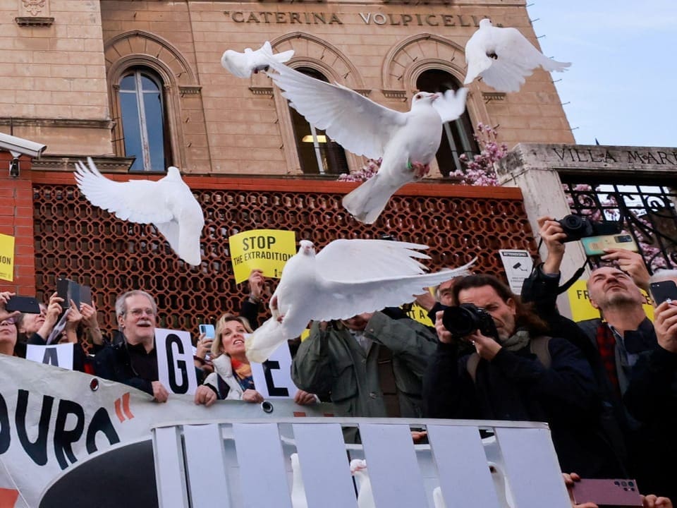 Demonstrierende lassen weisse Tauben fliegen.