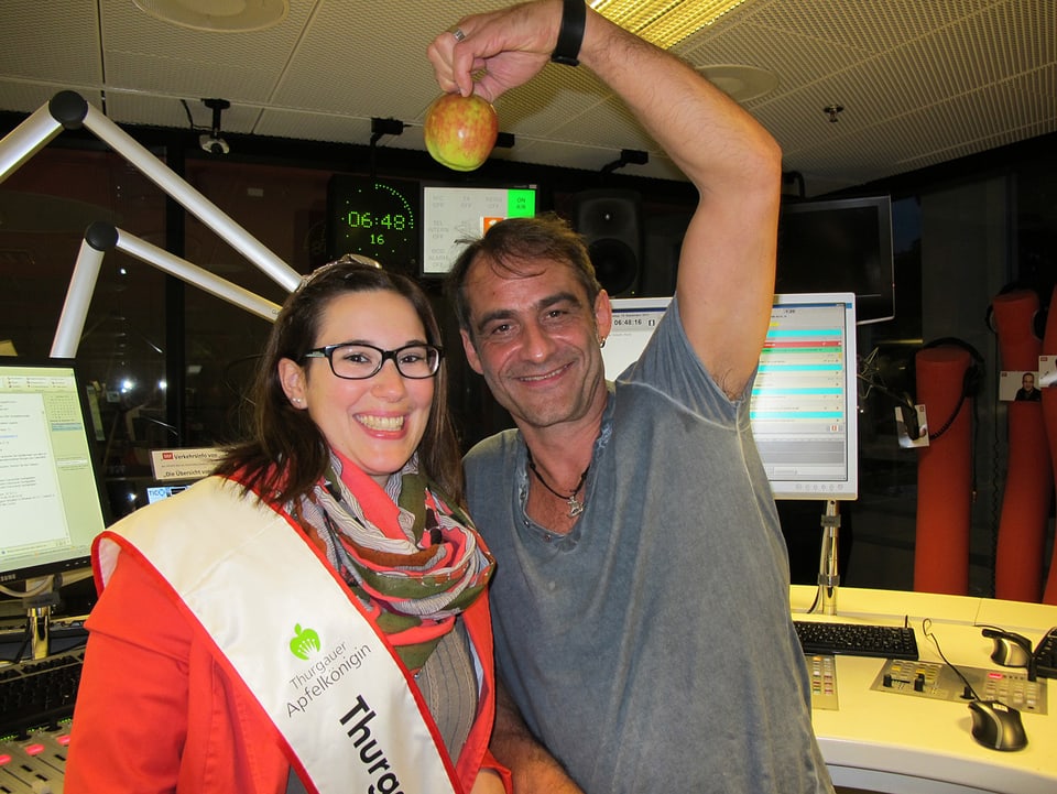 Stefanie König und Thomy Scherrer stehen nebeneinander im Radiostudio, Thomy Scherrer hält einen Apfel in der Hand.