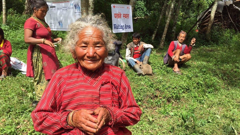 Eine ältere Frau steht lachend im «Warteraum» der Feldklinik