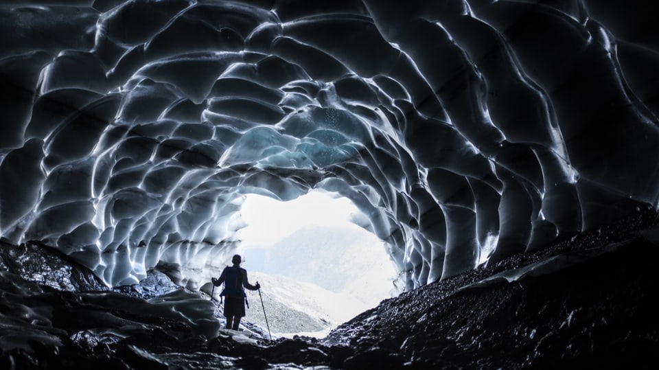 Mann durchschreitet Gletscherhöhle des Sardonagletschers in Vaettis