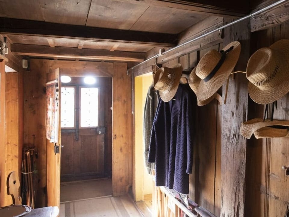 An der Garderobe hängen alte Hüte und Mäntel.