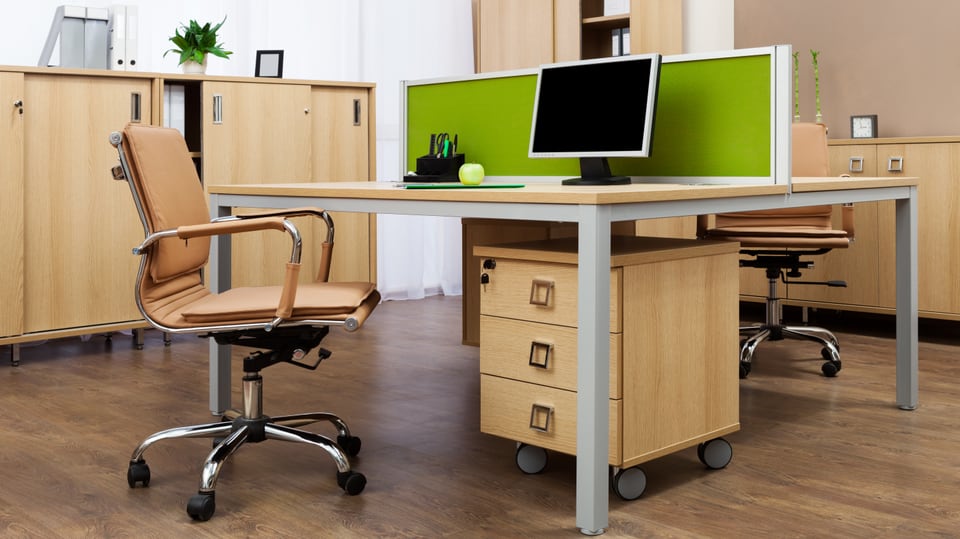 Blick in ein Büro mit leerem Tisch, zwei Stühlen und Büromöbeln.