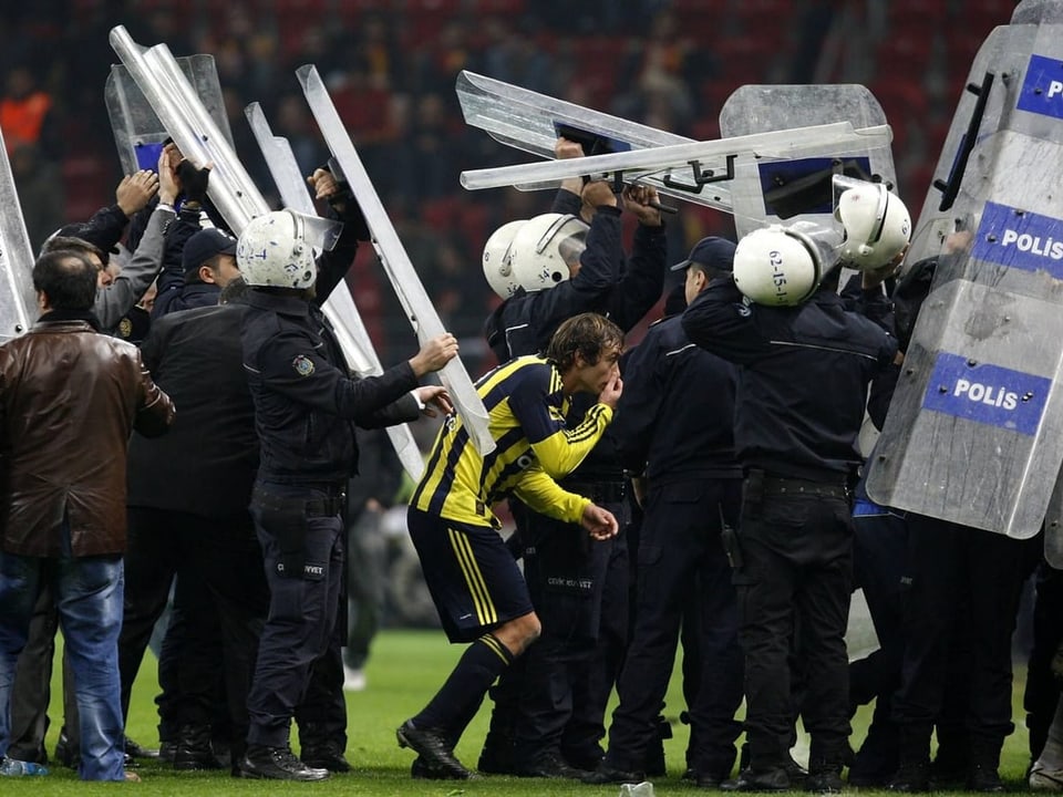 Fenerbache-Spieler verlässt von einem halben Dutzend Polizisten umringt das Spielfeld