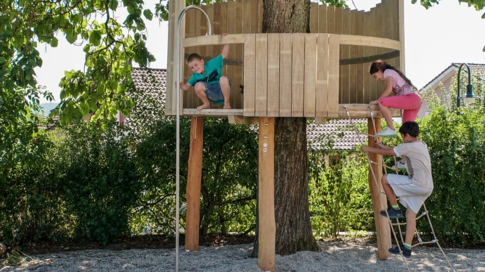 Kinder klettern in einem rundenBaumhaus