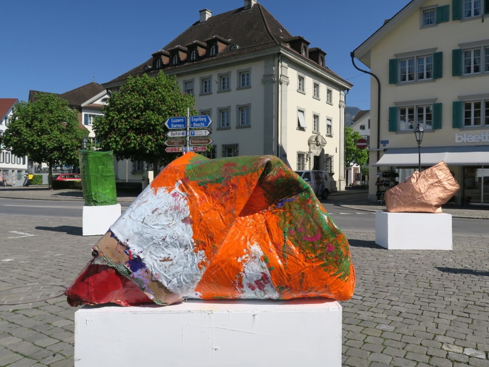 Orange-weiss-grüne Skulptur auf dem Dorfplatz Stans