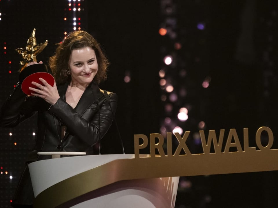 Frau in Lederjacke hält einen Preis bei der 'Prix Walo' Zeremonie
