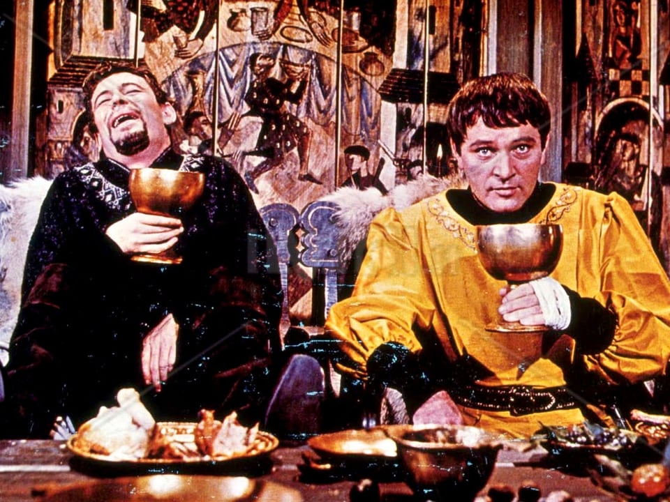 Zwei kostümierte Männer Trinken Wein aus grossen goldenen Kelchen.